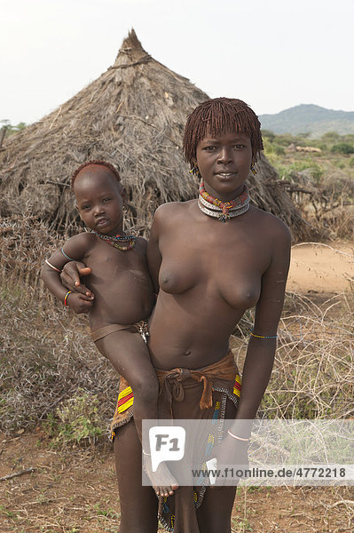 Junge Hamar Frau mit traditioneller Haarfrisur aus rotem Lehm hält ein Baby im Arm  Omo-Tal  Süd Äthiopien  Afrika
