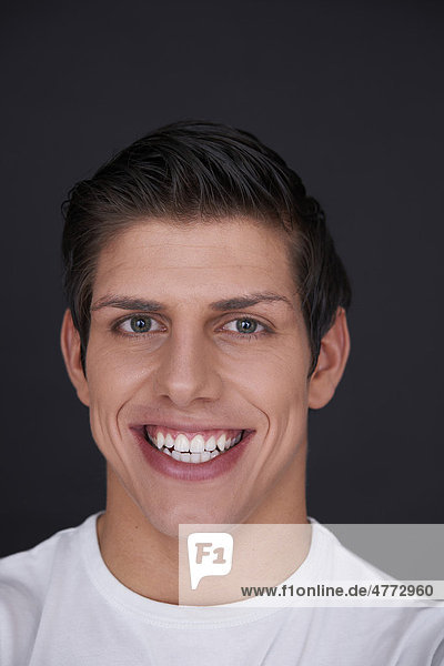 Junger Mann mit strahlend weißen Zähnen lächelt  Porträt