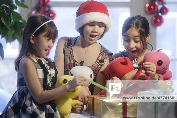 Drei Mädchen  10 und 12 Jahre  beim Auspacken der Geschenke zu Weihnachten