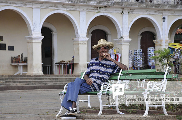 Mann sitzt auf Bank und raucht dicke Zigarre  Vinales  Kuba  Karibik  Mittelamerika