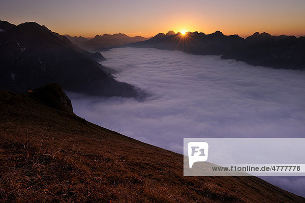 Gebirgstal unter Nebel mit Berggipfeln im Abendlicht  Allgäuer Alpen  Kleinwalsertal  Vorarlberg  Österreich  Europa