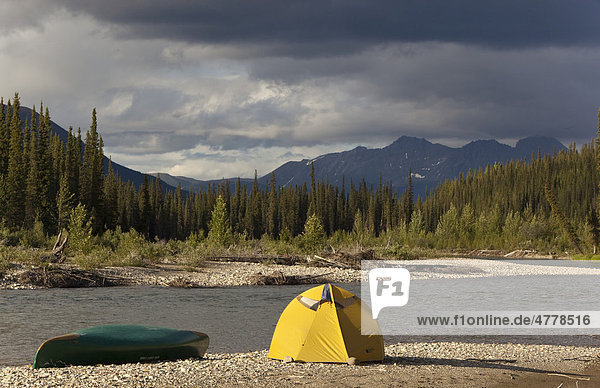 Lagerplatz mit Zelt und Kanu am Schotterufer  Pelly Mountains Gebirgszug hinten  Upper Liard River  Yukon Territory  Kanada