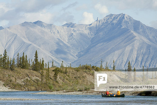 Kanufahrer paddeln auf dem Wind River  Kanu  hinten nördliche Mackenzie Mountains Gebirgskette  Yukon Territorium  Kanada