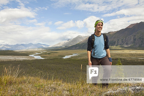 Young woman hiking  arctic tundra  Wind River and Mackenzie Mountains behind  Yukon Territory  Canada