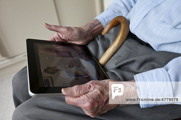 Senior betrachtet Fotos auf seinem iPad  Nahaufnahme Hände
