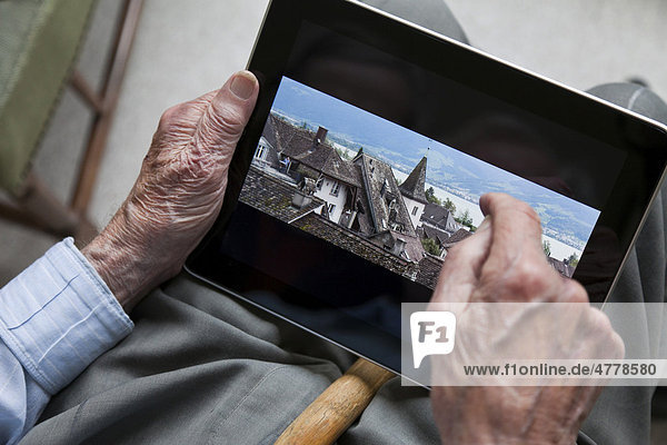 Senior betrachtet Foto von Dächern in Rappersvil  Zürichsee  Schweiz  auf seinem iPad  Nahaufnahme Hände