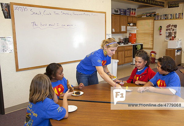 An Americorps volunteer serves a snack to children at PALS  an after-school program operated by La Puente  a nonprofit agency providing social services in Colorado's San Luis Valley  where much of the population lives below the poverty level  Alamosa  Colorado  USA