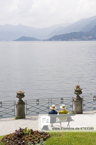 Elderly couple sitting on garden bench beside lake  Villa Monastero  Varenna  Lake Como  Lombardy  Italy  Europe