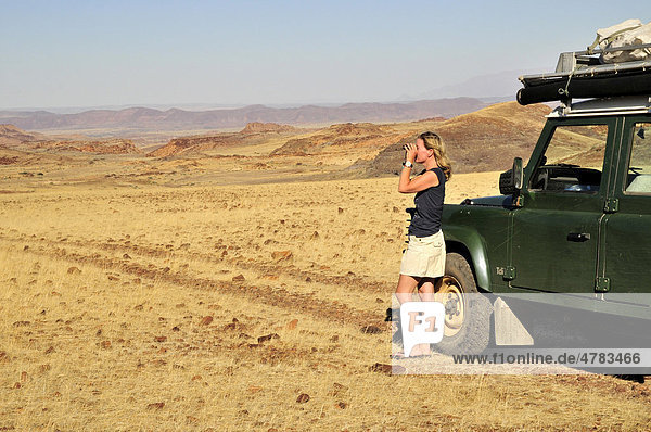 Safari tourist looking through binoculars  Mik Mountains  Damaraland  Namibia  Africa