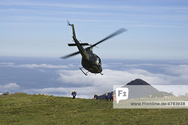 Hubschrauber wird von Rettungskräften eingewiesen  Bundeswehrhelikopter im Landeanflug  Chiemgauer Alpen  Bayern  Deutschland  Europa