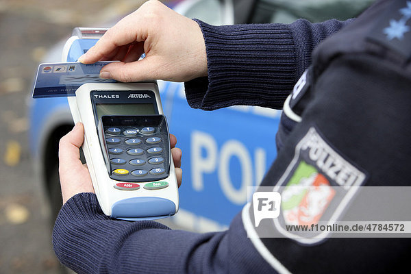 Police officer with BARVUS device for cashless payment of caution money  fines  tickets with credit card
