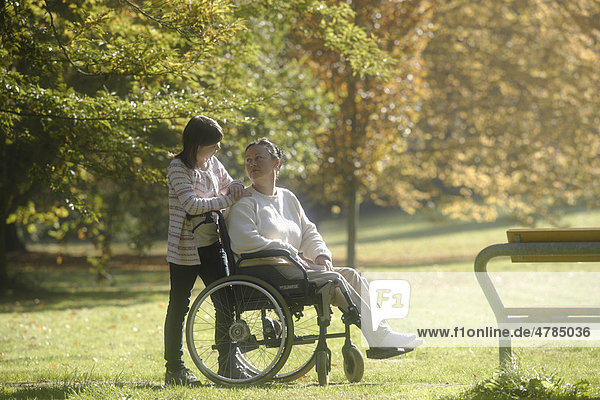 Frau im Rollstuhl mit ihrer Tochter im Park