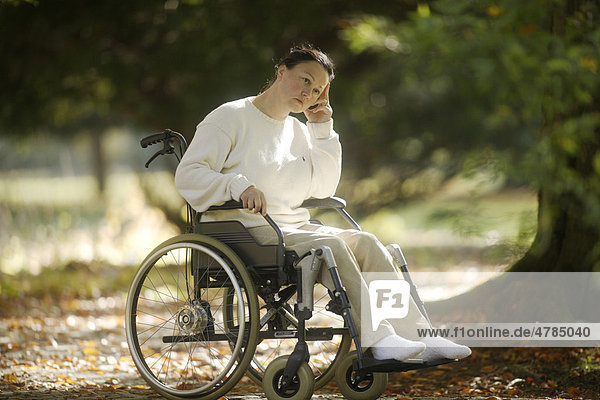 Frau sitzt nachdenklich im Rollstuhl