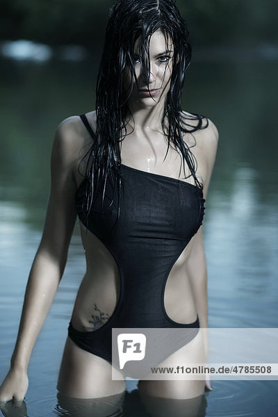 Junge Frau in einem schwarzen Badeanzug und mit nassen Haaren beim Baden in einem See