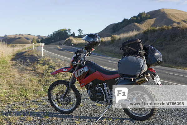 Schwer bepacktes Enduro Motorrad an einer einsamen Landstraße  Nordinsel  Neuseeland