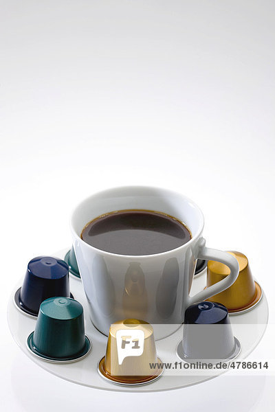 Tasse mit frisch gebrühtem Kaffee und Kaffeekapseln