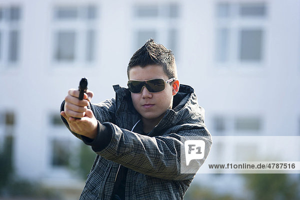 Teenager with a Softair pistol on a school playground  posed scene