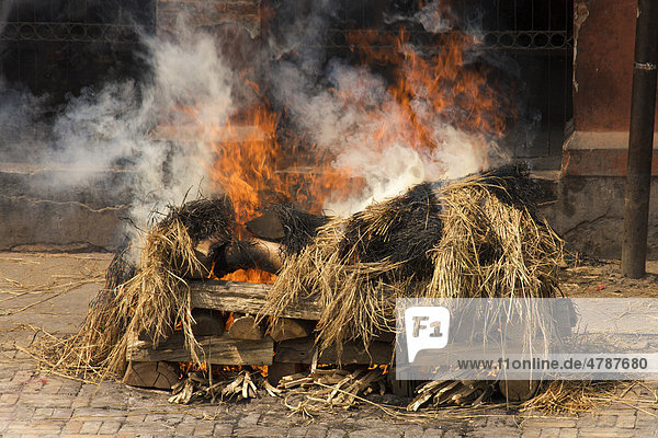 Brennender Scheiterhaufen mit teilweise sichtbarem Leichnam bei traditionellem Begräbnis  Pashupatinath  Nepal  Asien