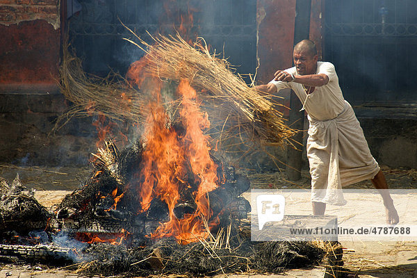 Unberührbarer Priester aus der untersten Kaste hält Scheiterhaufen bei traditioneller Leichenverbrennung am Brennen  Pashupatinath  Nepal  Asien