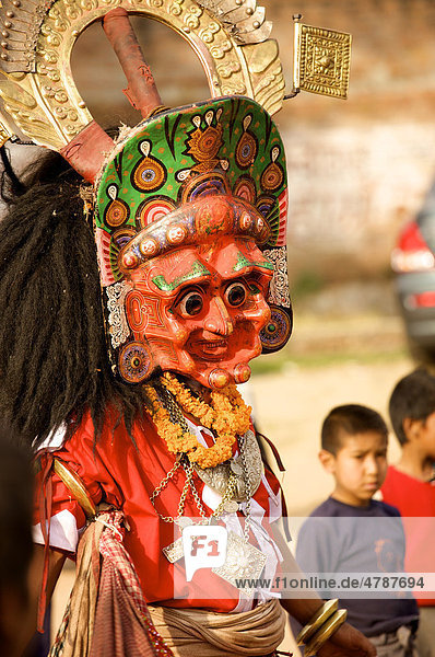 Verkleideter Mann mit roter Maske und traditionellen Kleidern tanzt für Kinder  Bhaktapur  Nepal  Asien