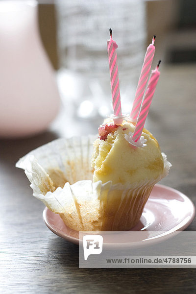 Halber Muffin mit rosa Geburtstagskerzen