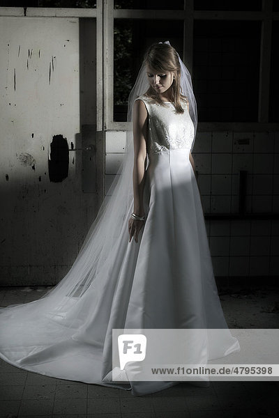 Junge Frau in einem Hochzeitskleid mit Schleier in einer urbanen Location