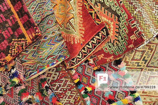 Bunte  gewebte Kissenbezüge mit traditionellen Ornamenten der Berber und Araber sind bei einem Händler im Souk  Basar  zum Verkauf ausgelegt  Marokko  Afrika