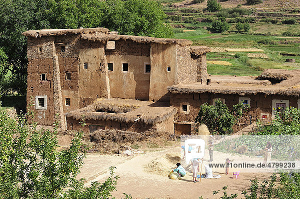 Eine Kasbah  Wohnburg der Berber aus Lehm  auf dem Platz vor der Kasbah wird von den Bewohnern Spreu und Stroh von den Getreidekörnern getrennt  Ait Bouguemez  Hoher Atlas  Marokko  Afrika