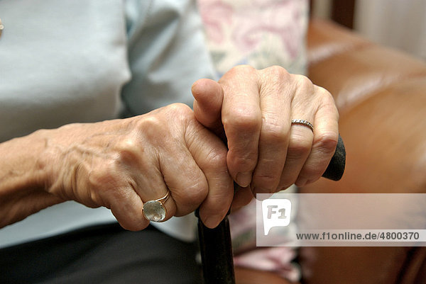 Hände einer älteren Frau mit einem Spazierstock