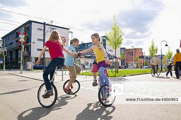 Children on unicycles in a play street  Vauban district in Freiburg im Breisgau  Baden-Wuerttemburg  Germany  Europe