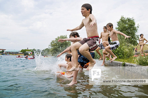 Group of young people jumping into a lake  Freiburg im Breisgau  Baden-Wuerttemburg  Germany  Europe