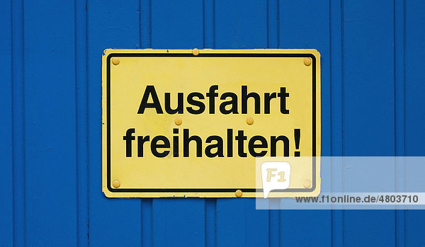 Schild  Ausfahrt freihalten!  gelb auf blauem Tor