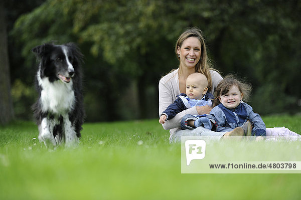 Glückliche Mutter mit ihrer dreijährigen Tocher  ihrem sechs Monate alten Sohn und einem Hund