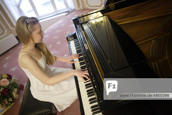 Woman in a white dress playing a grand piano