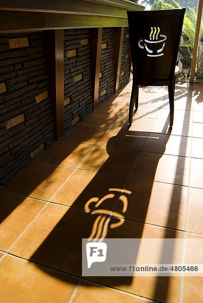 Stuhl mit Kaffee-Logo wirft langen Schatten