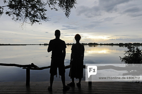 Touristen sitzen in Abendstimmung auf einer Terrasse über der Guma Lagune  Guma Lagoon  Okavango-Delta  Botsuana  Afrika