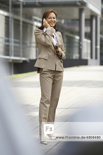 Business woman  45 years  talking on a mobile phone in front of office building