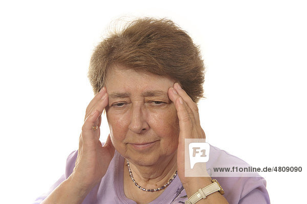 Seniorin mit Kopfschmerzen fasst sich an die Stirn