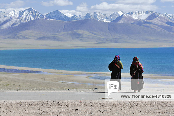 Tibetan pilgrims  snow-covered peaks of the Nyenchen Thanglha Mountains  Namtso Lake  Heavenly Lake  Tibet  China  Asia