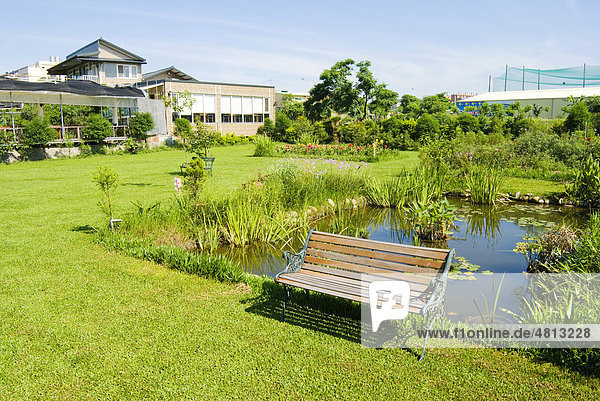 Garten mit Sitzbank  Teich und leuchtend grünen Wiesen