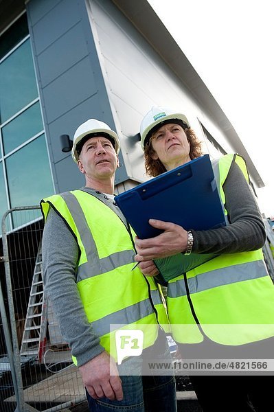 Two people making a health and safety inspection report on a construction site UK