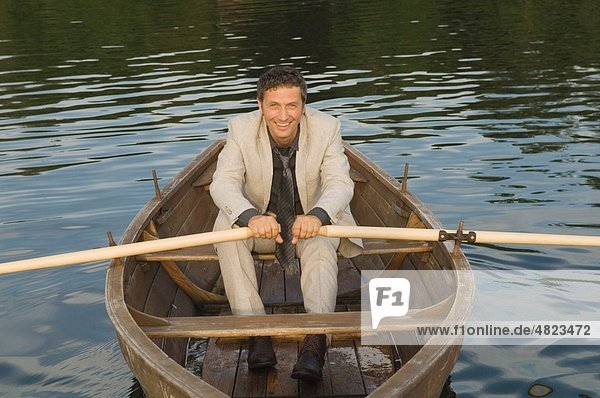 Wesslinger See  Business man rowing boat in lake after work