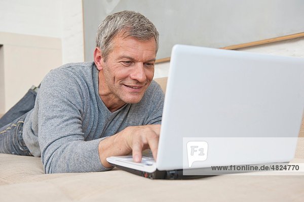 Erwachsener Mann mit Laptop zu Hause