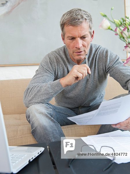 Mature man doing paperwork with laptop