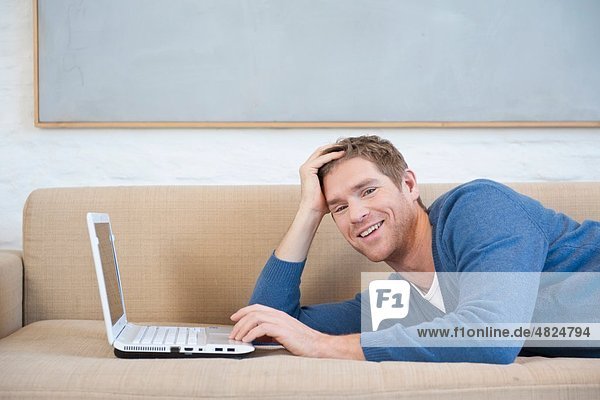 Mid adult man using laptop  smiling  portrait