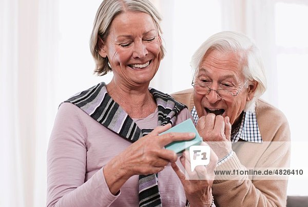 Senior Mann überraschend Frau mit Geschenk  lächelnd