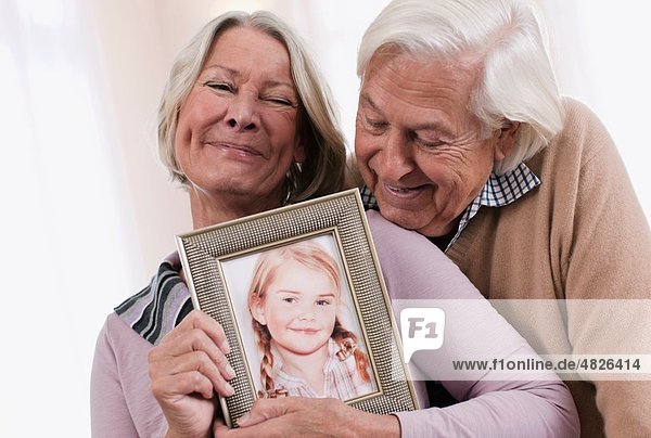 Germany  Wakendorf  Grandparents holding granddaughter photograph