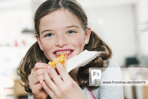 Ein Mädchen isst eine Scheibe Pizza.