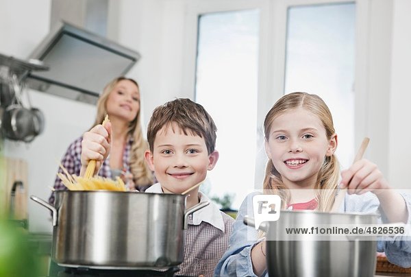 Deutschland    Kinder kochen Spaghetti in der Küche  Mutter im Hintergrund