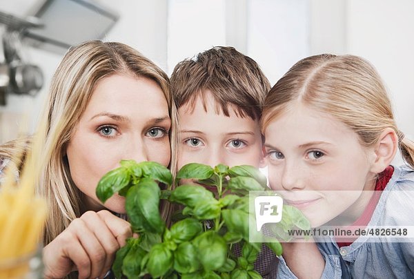 Deutschland    Mutter und Kinder riechendes Basilikum  Portrait